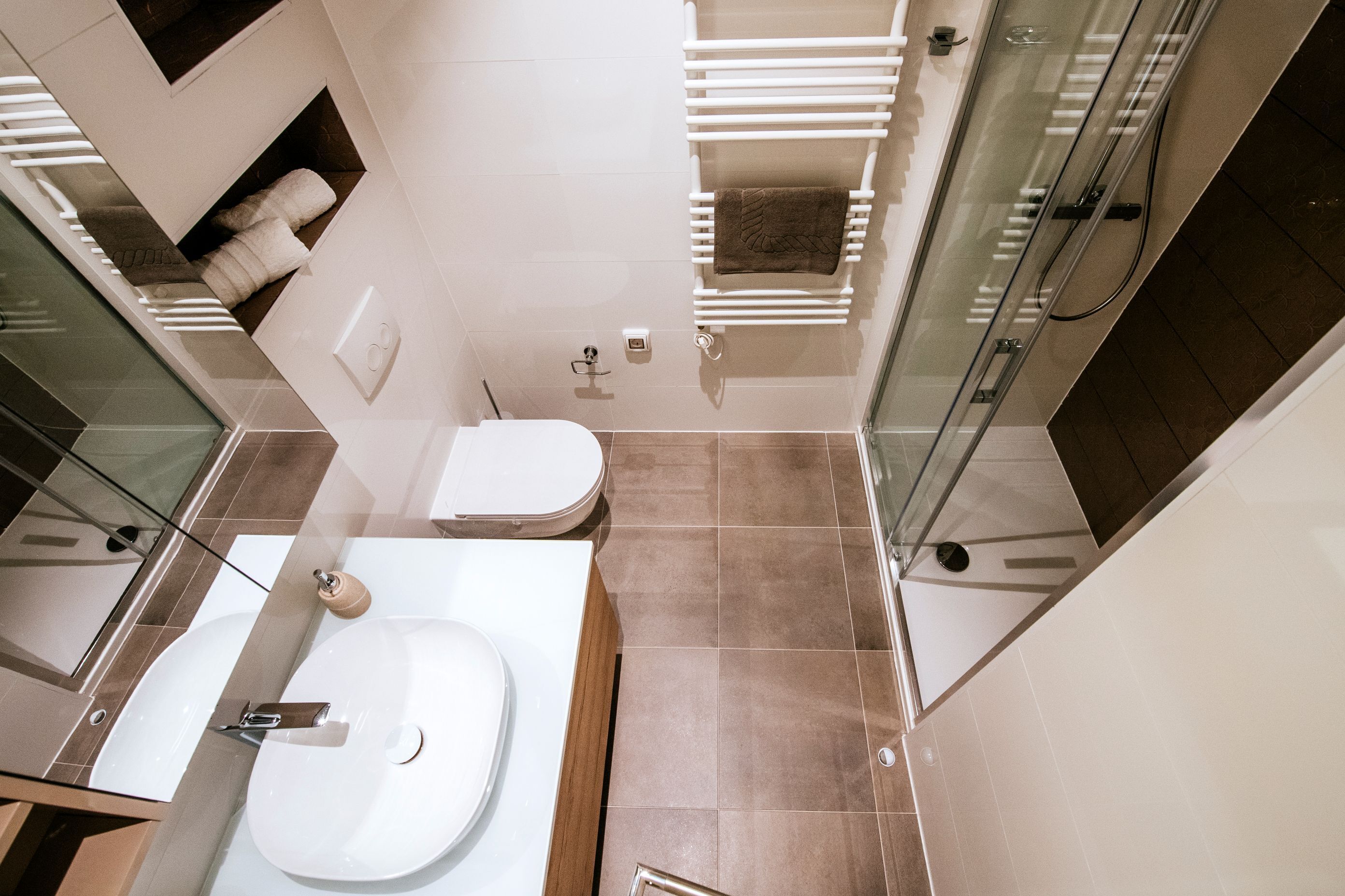 Un baño moderno con cabina de ducha de vidrio, un lavamanos blanco y un inodoro.