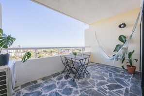 A balcony with a stone floor, a table with chairs, a hammock, and potted plants. - Charming Flat With Amazing sea Line View (Cascais)