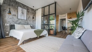 A modern bedroom with a bed, a sofa, a large window, and a potted plant. - Charming Flat With Amazing sea Line View (Cascais)