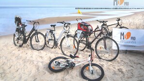 Bicycles parked on a sandy beach with a banner for 'MS PRO APARTMENTY KOLOBRZEG'. - MS Pro Apartamenty AQUARIUS (Kolobrzeg)
