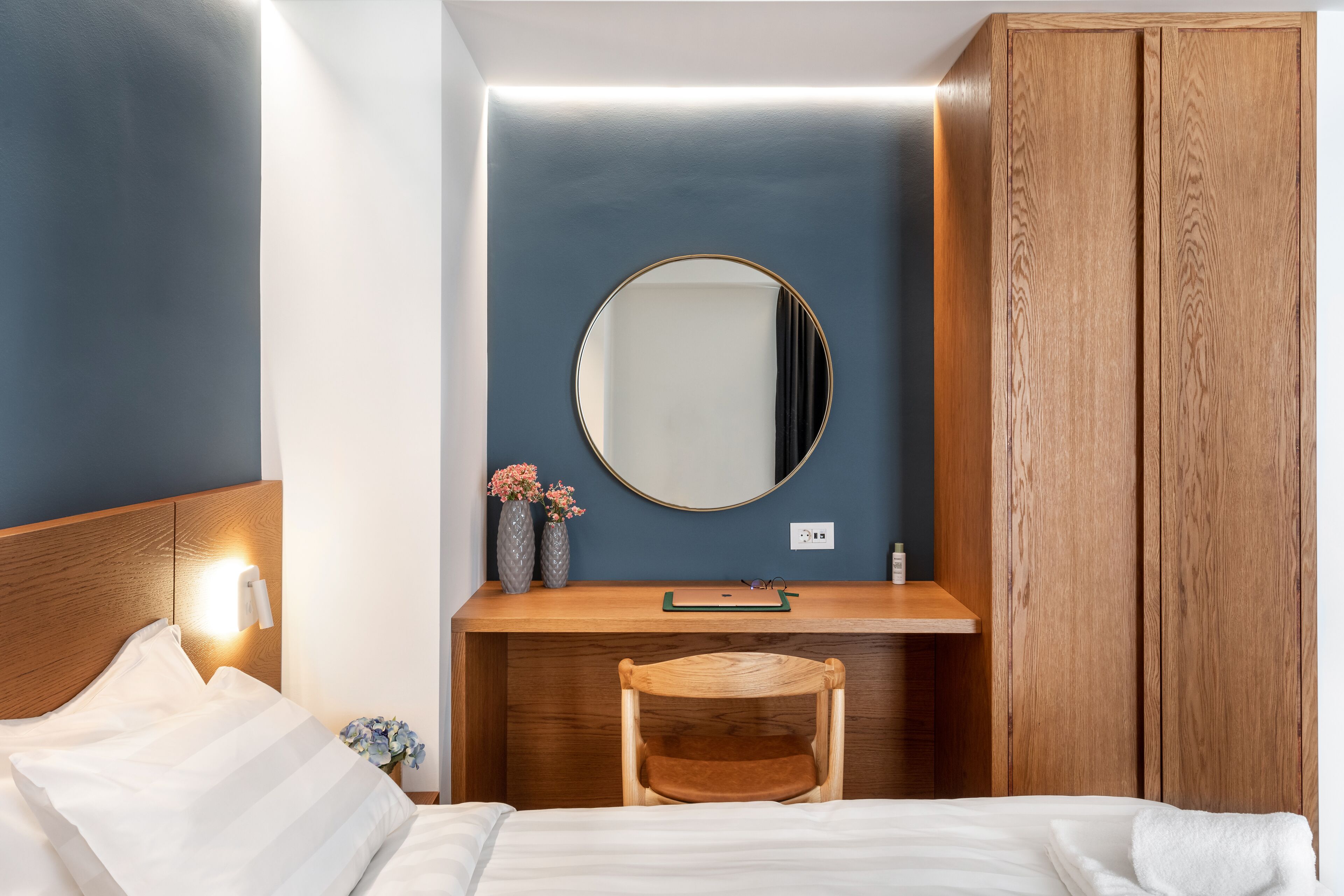 A bedroom with a wooden bed, a desk with a mirror, and a wardrobe.