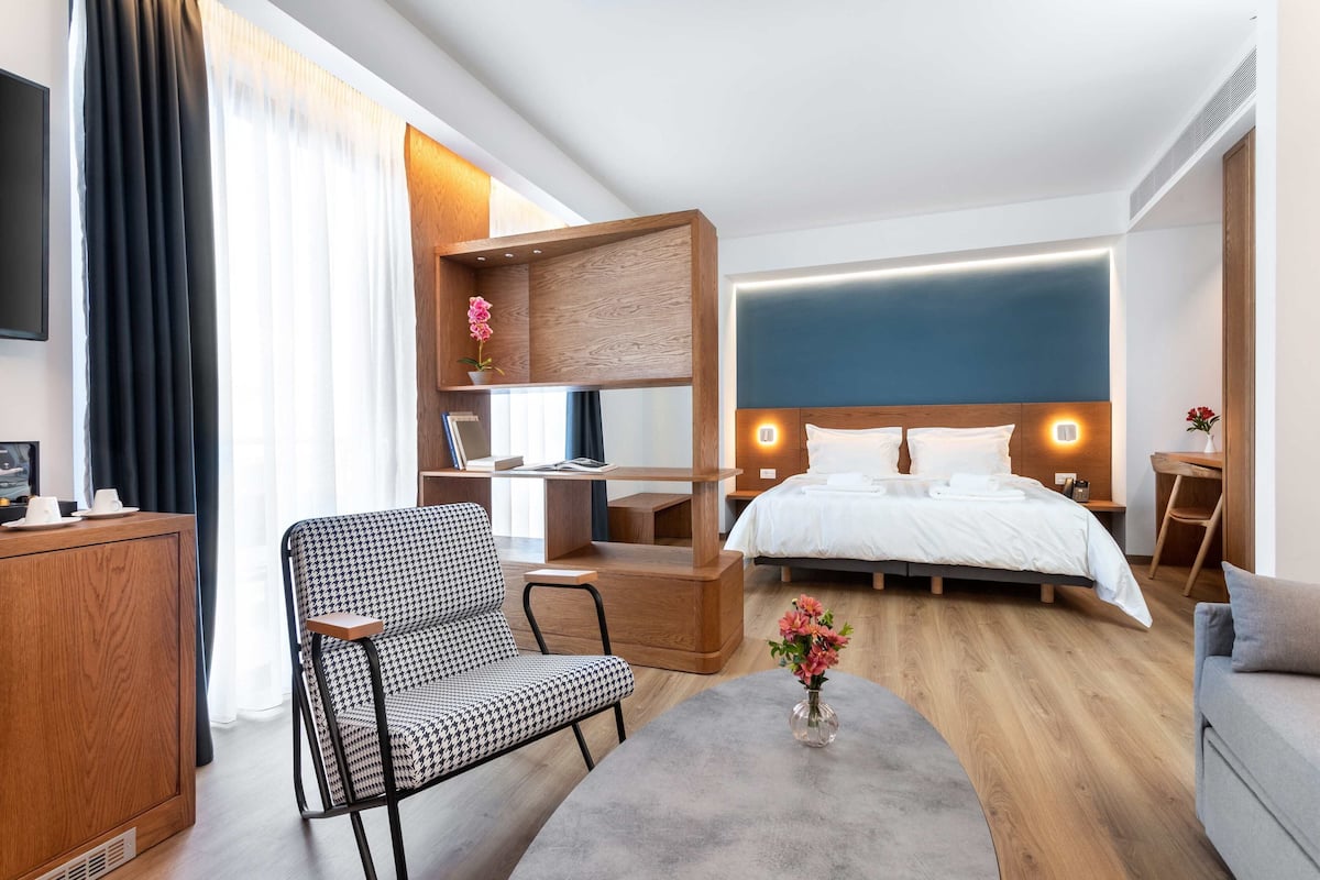 Una habitación de hotel con cama, escritorio, silla, sofá y televisor.