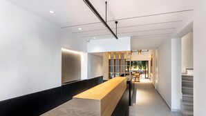 Un área de recepción moderna con un largo mostrador de madera, una escalera y vistas a un comedor.