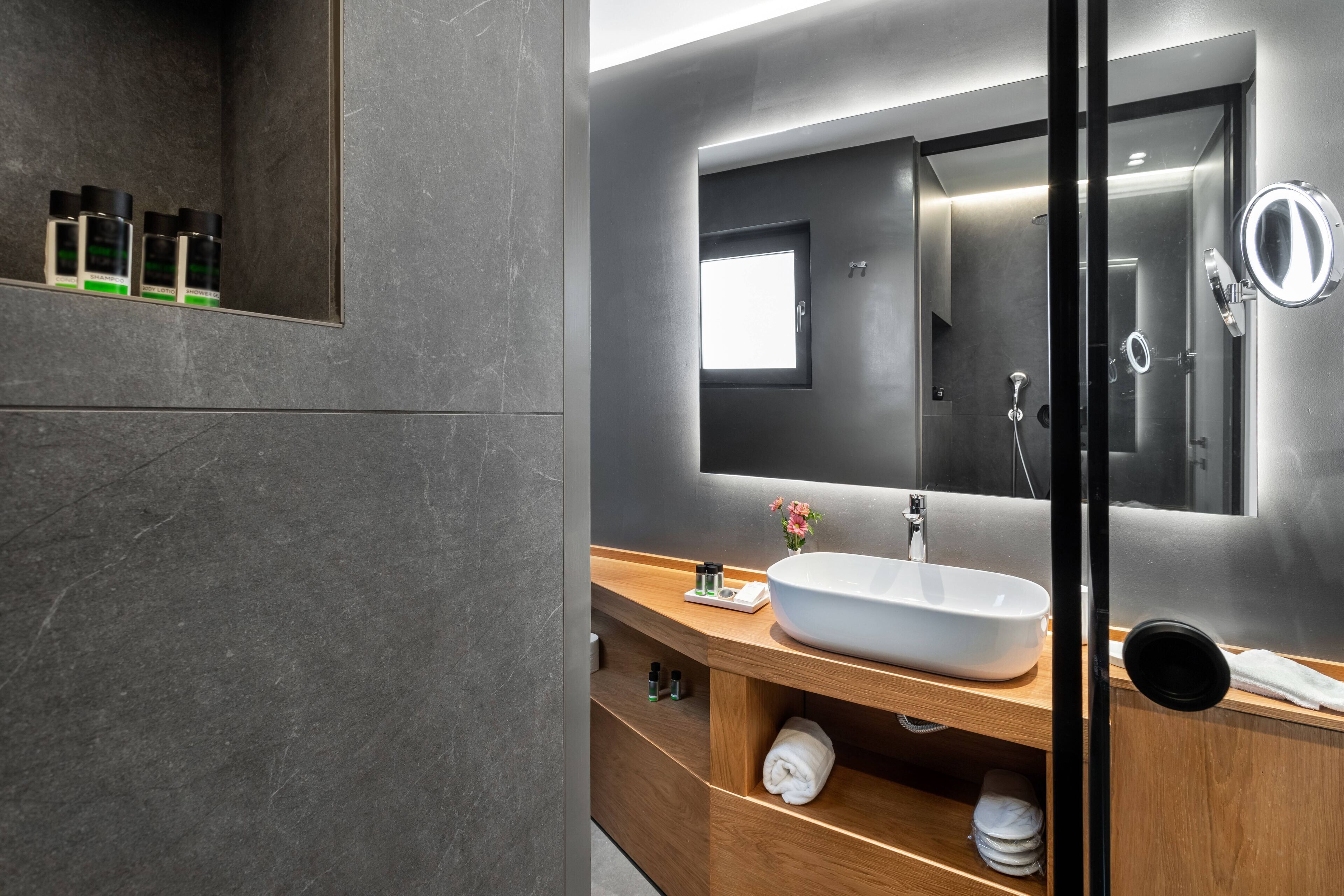 Un baño moderno con un espejo grande, un lavabo blanco y un mueble de tocador de madera.