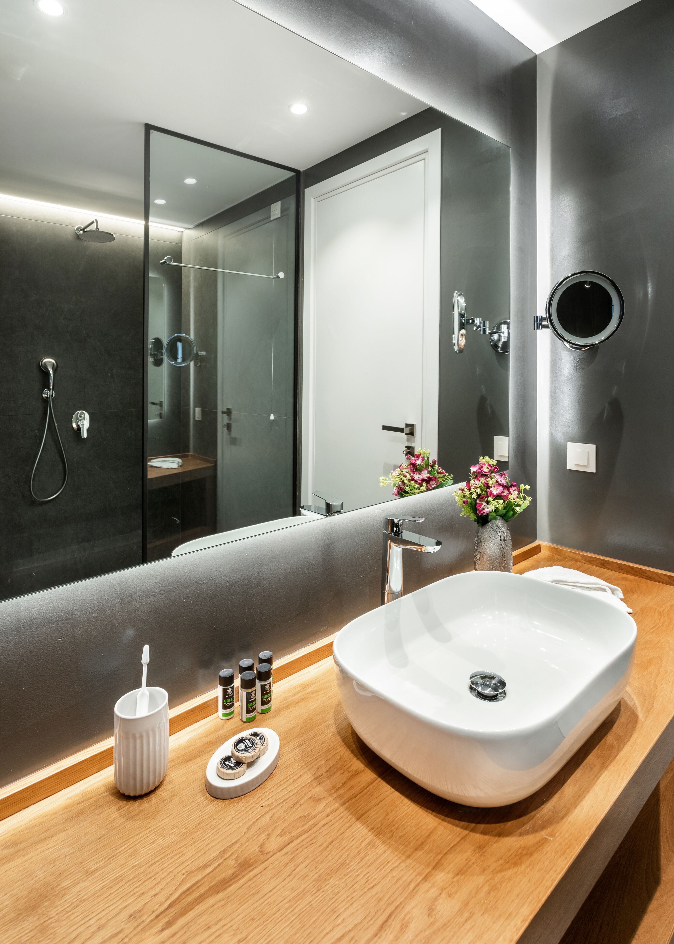 A modern bathroom with a large mirror, a freestanding bathtub, and a vanity with a sink and toiletries.
