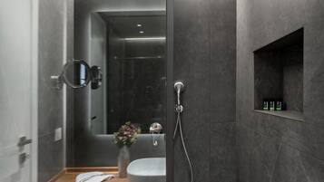 Un baño moderno con cabina de ducha de vidrio, tocador de madera, lavamanos y espejo.