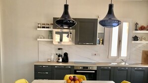 A modern kitchen with a central island, overhead lighting, and a fruit bowl on the island.