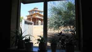 A window with potted plants and a view of a wooden house and trees. - Powell Ranch-Pool & Jacuzzi on Beautiful Farm (Exeter)