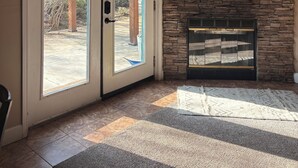 A room with a stone wall, a fireplace, and a large window with a view of trees. - Powell Ranch-Pool & Jacuzzi on Beautiful Farm (Exeter)