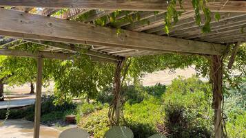 A covered patio area with a wooden pergola, outdoor furniture, and lush greenery.