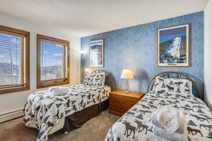 A bedroom with two beds, wooden headboards, a nightstand, and a poster on the wall.