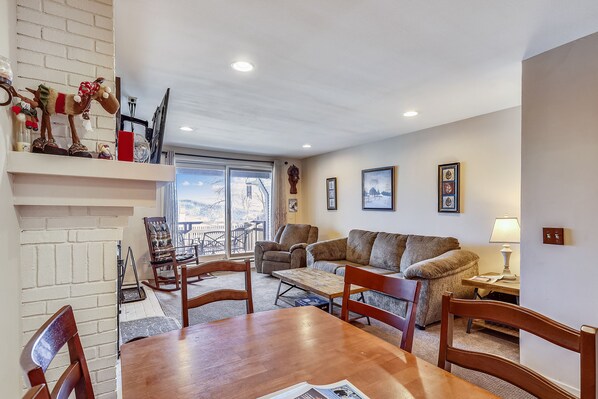 A cozy living room with a fireplace, a dining table, and a sofa.