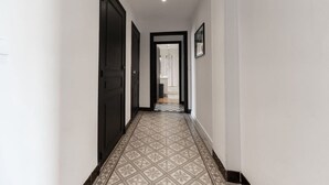 A hallway with patterned flooring, dark doors, and a framed picture on the wall.