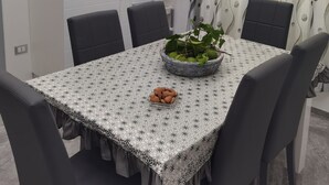 A dining area with a table set for four, a kitchen with white cabinetry, and a patterned curtain. - La Casa del Corso (Avola)