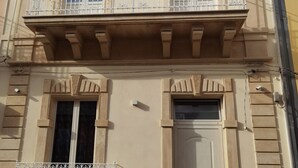 A two-story building with a balcony on the upper floor and a door on the lower floor. - La Casa del Corso (Avola)