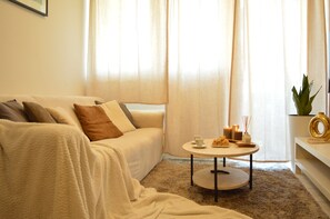 A cozy living room with a sofa, a round coffee table, and a plant.