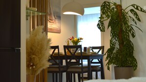 Un comedor con una mesa, sillas, una lámpara colgante y una planta en maceta.