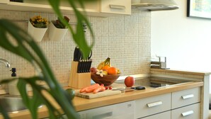 Una cocina con salpicadero de azulejos, un frutero, una tabla de cortar con verduras y un lavavajillas.