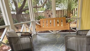 A covered porch with a patterned floor, wicker furniture, and a wooden bench. - Adorable 3 bed, 2 bath Cottage in Glynn Haven SD (Saint Simons Island)