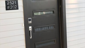 Una puerta moderna con un cartel con número, un teclado numérico y un buzón.