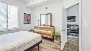 Un dormitorio con cama, cómoda, espejo y ventana.