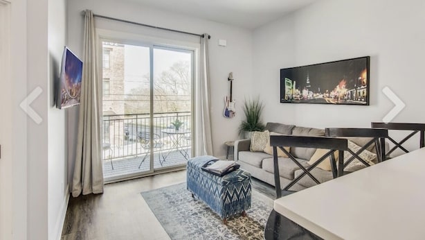 Una sala de estar moderna con un sofá, un reposapiés y una mesa de comedor.