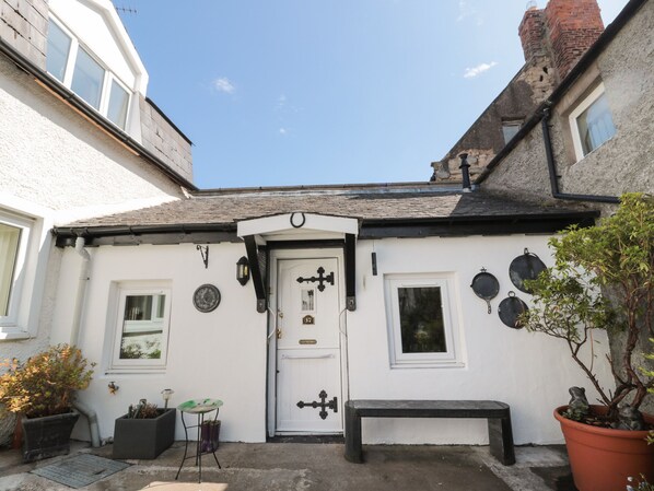 A white building with a black door, a small window, and a bench outside.