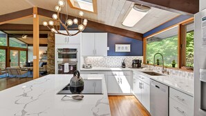 A modern kitchen with a central island, built-in appliances, and a skylight.