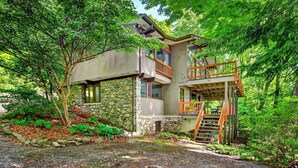 A two-story house with a stone foundation, wooden balcony, and a staircase leading to the upper level.