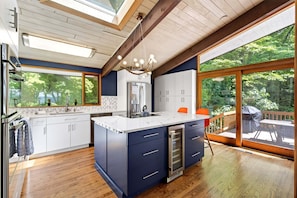 Una cocina moderna con una isla central, vigas de madera, ventanas amplias y vistas al exterior.