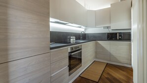 A modern kitchen with light wood cabinetry, a stainless steel oven, and a black countertop. - New Deal - APT with Terrace & Jacuzzi (Palmanova)