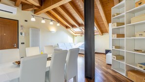 A modern interior with a dining area, white chairs, a wooden ceiling, and built-in shelving with storage boxes. - New Deal - APT with Terrace & Jacuzzi (Palmanova)