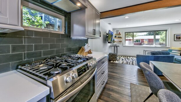 Een moderne keuken met een gasfornuis, roestvrijstalen apparatuur en een groot raam.