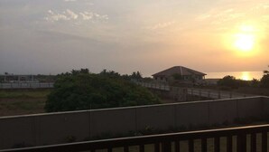 A sunset over a body of water with a building and greenery in the foreground. - A peaceful family home with brilliant sea views, set within private grounds. (Oshiyie)
