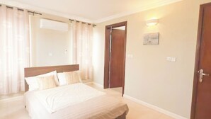 A bedroom with a bed, curtains, a door, and a wall-mounted light. - A peaceful family home with brilliant sea views, set within private grounds. (Oshiyie)