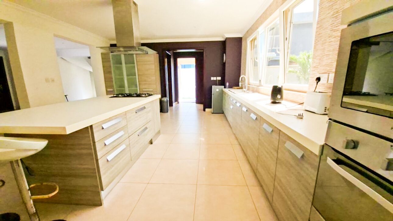 A modern kitchen with a central island, built-in appliances, and a view to the dining area.