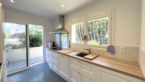 A modern kitchen with a large window, a built-in stove, and a sliding glass door leading to a patio.