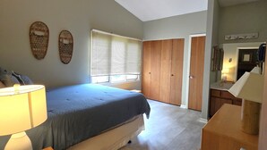 Un dormitorio con cama, mesitas de noche, armario y ventana con persianas.