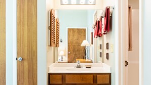 Un baño con tocador de madera, espejo y lavamanos.