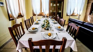 A dining room with a long table set for a meal, surrounded by wooden chairs. - Villa Ellea by pugliadamare (San Michele Salentino)