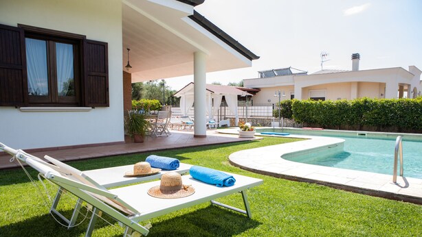 A poolside area with lounge chairs, a sun umbrella, and a pool. - Villa Ellea by pugliadamare (San Michele Salentino)