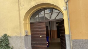 An arched entrance to a building with a wooden door and a small potted plant beside it.