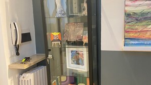 A glass-fronted cabinet with various items on display, a radiator, and a painting on the wall.