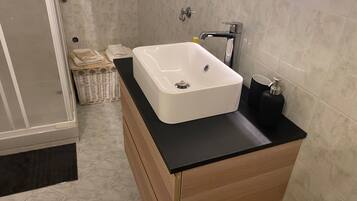 Un bagno con lavandino bianco, piano di lavoro nero e mobili in legno.