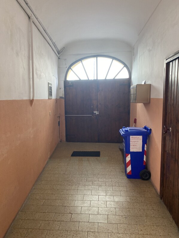 A hallway with a wooden door, a trash bin, and a mailbox.