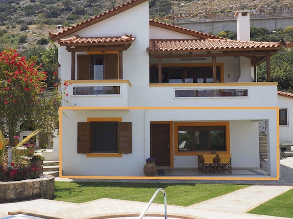 Une maison à deux étages avec un balcon, une terrasse dotée de mobilier d’extérieur et une piscine.