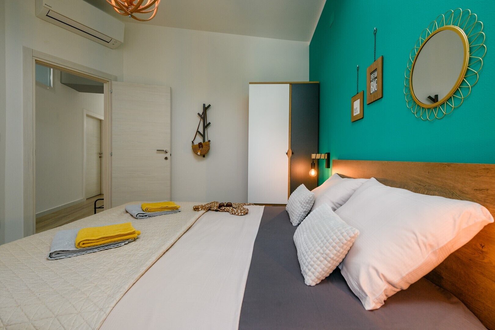 A bedroom with a bed, a mirror, a wall clock, and a door.