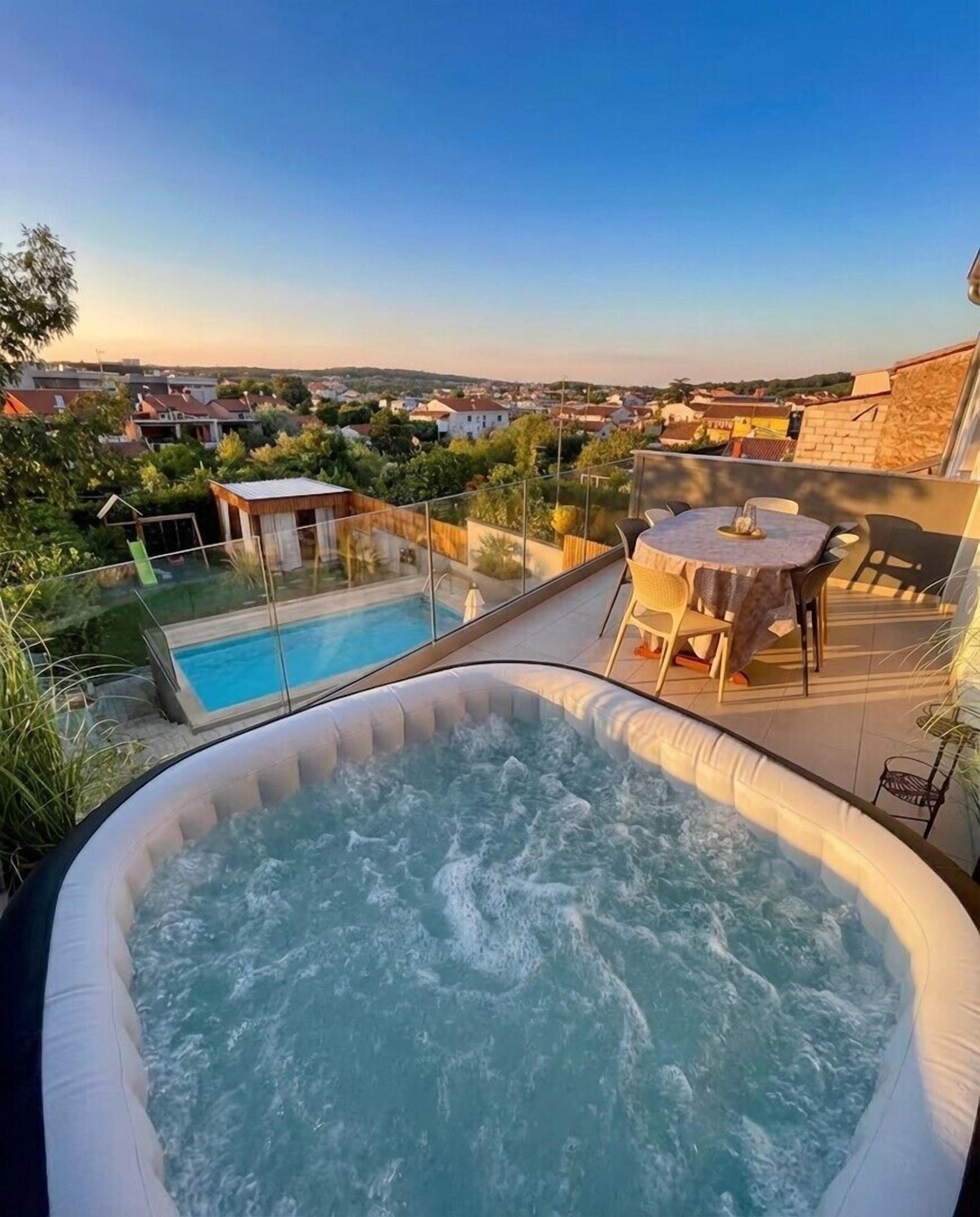 Ein Whirlpool im Freien mit Blick auf ein Wohngebiet und einen Swimmingpool.