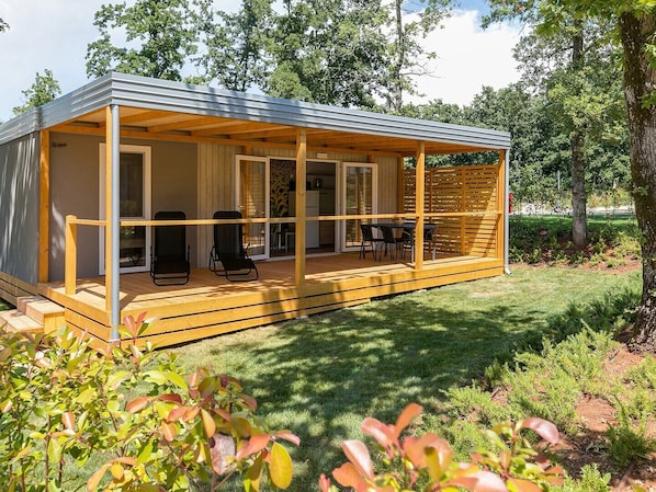 A modern, single-story cabin with a covered porch, sliding glass doors, and a small outdoor seating area.