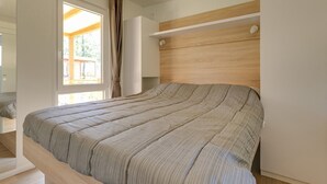 Un dormitorio moderno con una cama grande, un cabecero de madera y una ventana con cortinas.